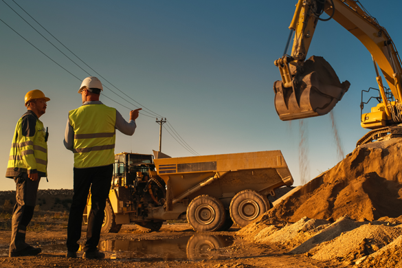 two construction workers looking over a project plan while on a busy worksite
